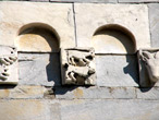 Stazzema (Lucca), chiesa di S. Maria Assunta, facciata: teoria di archetti pensili con mensole figurate, particolare.